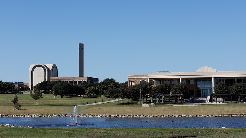 campus in front of a large pond with a fountaion in the middle